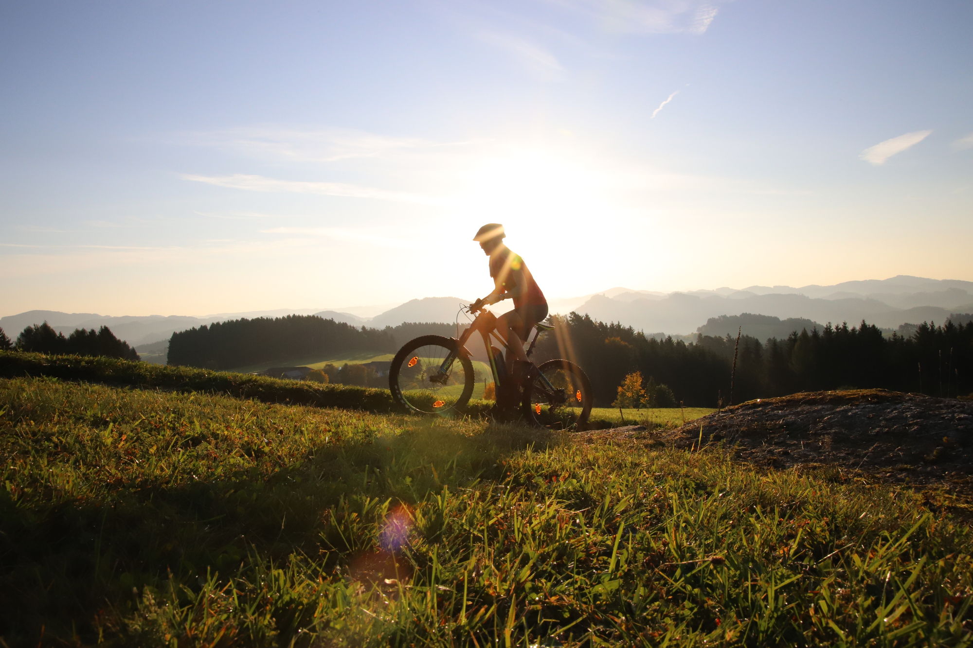 Ein Mountainbiker fährt auf der Tour de Alm durch die hügelige Landschaft der Mühlviertler Alm
